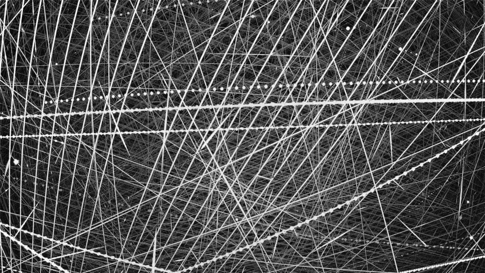 Stacked night-sky image covered in straight satellite trails